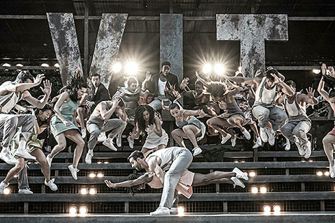 The production is staged on a dilapidated seating bleacher (photo: Marc Brenner)